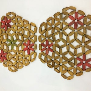 Pode incluir: Dois  copos de madeira com um design floral. Os  copos são feitos de pequenas peças de madeira ovais que são tecidas juntas para criar um padrão de flores. As flores são pintadas em tons de vermelho e verde.