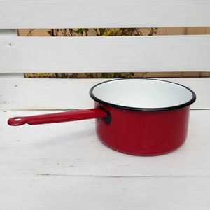 Peut inclure: Une casserole en émail rouge avec un intérieur blanc et un bord noir. La casserole a une poignée rouge.