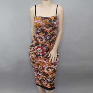 May include: A bodycon dress with a colorful paisley pattern. The dress features a black base with a vibrant design in shades of orange, red, yellow, and pink. It has thin black straps and a knee-length hemline.