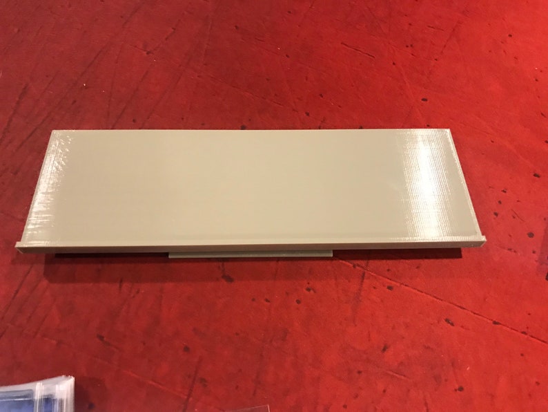 Op de afbeelding: Een lichtbeige rechthoekige plank met een glad, licht getextureerd oppervlak. De plank is gemaakt van plastic en heeft een eenvoudig, modern ontwerp.