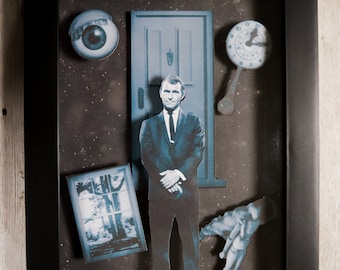 May include: A black framed shadow box with a scene from "The Twilight Zone" featuring a man in a suit, a door, a clock, an eye, and a window. The text "A scene from The Twilight Zone" is printed on the bottom of the box.