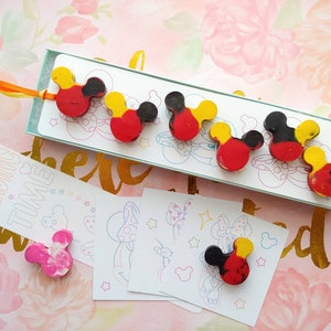 May include: A set of five red, yellow, and black Mickey Mouse head shaped crayons in a box with a white background. The box has the text "Reading Time" on it. There are also four coloring pages with Mickey Mouse images.