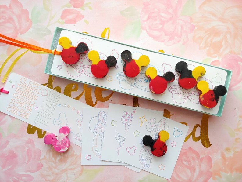 May include: A set of five red, yellow, and black Mickey Mouse head shaped crayons in a box with a white background. The box has the text "Reading Time" on it. There are also four coloring pages with Mickey Mouse images.