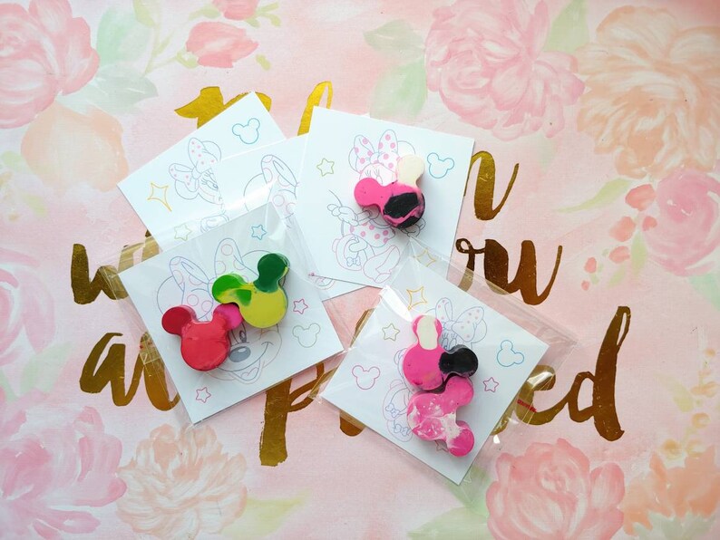 May include: Four small bags with white cardstock inside, each featuring a black and white line drawing of a cartoon mouse with large ears. Each bag contains a set of three small, colorful, hand-painted, wax crayons shaped like the cartoon mouse.