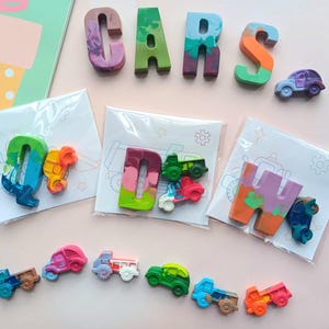 May include: A set of colorful crayon letters spelling out "CARS" with a variety of small crayon cars in individual bags. Each bag has a different letter and a different car design.