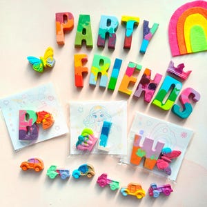May include: A set of colorful crayon letters spelling "PARTY FRIENDS" with a rainbow felt cutout, a butterfly, and small cars. The letters are packaged in clear bags with coloring pages.