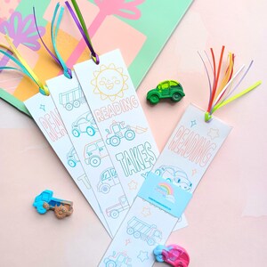 May include: Three colorful bookmarks with a vehicle theme. Each bookmark features a different design with a sun, a truck, and a car. The bookmarks have a white background with colorful outlines and the text "Reading Takes You..." on the bottom.