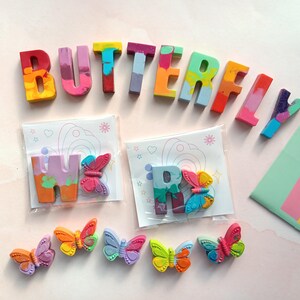 May include: A set of colorful crayon letters spelling out the word "BUTTERFLY" with two smaller crayon letters "W" and "R" and several colorful butterfly shaped crayons.
