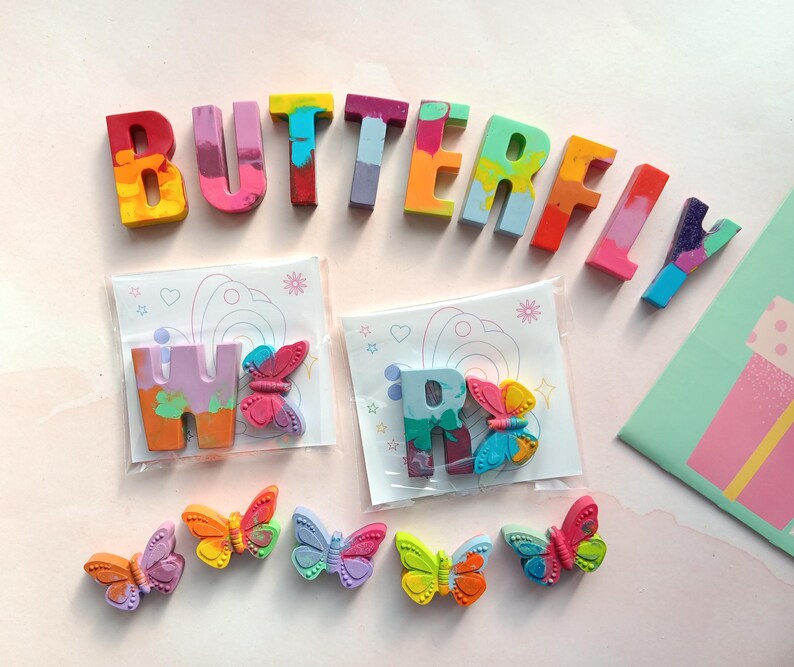 May include: A set of colorful crayon letters spelling out the word "BUTTERFLY" with two smaller crayon letters "W" and "R" and several colorful butterfly shaped crayons.