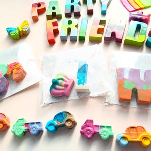 May include: A set of colorful crayon letters spelling out "Party Friends" with a crown, butterfly, and cars. The letters are packaged in clear plastic bags.