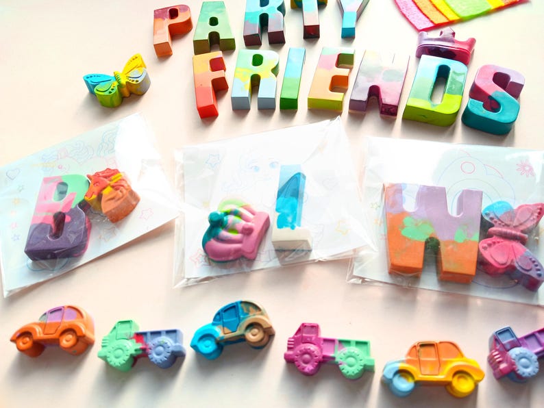 May include: A set of colorful crayon letters spelling out "Party Friends" with a crown, butterfly, and cars. The letters are packaged in clear plastic bags.