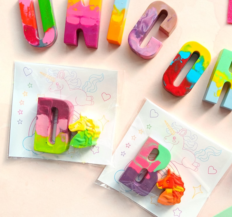 May include: A set of colorful crayon letters spelling out the word "UNICORN" with a unicorn illustration and a letter D and a unicorn crayon in a clear plastic bag.