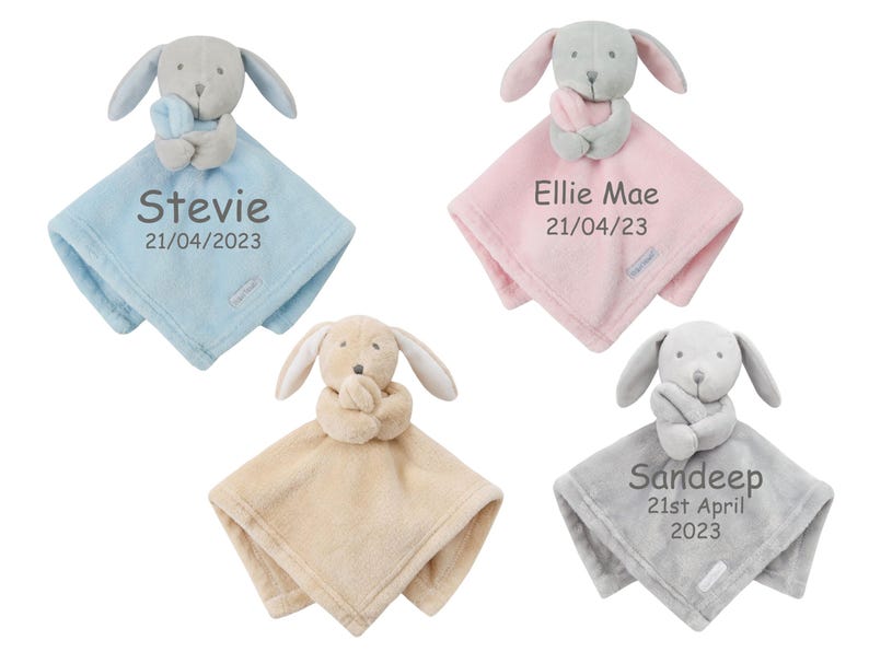 May include: Four personalized baby blankets with a plush grey dog attached. The blankets are blue, pink, beige, and grey. The blankets are embroidered with names and dates.