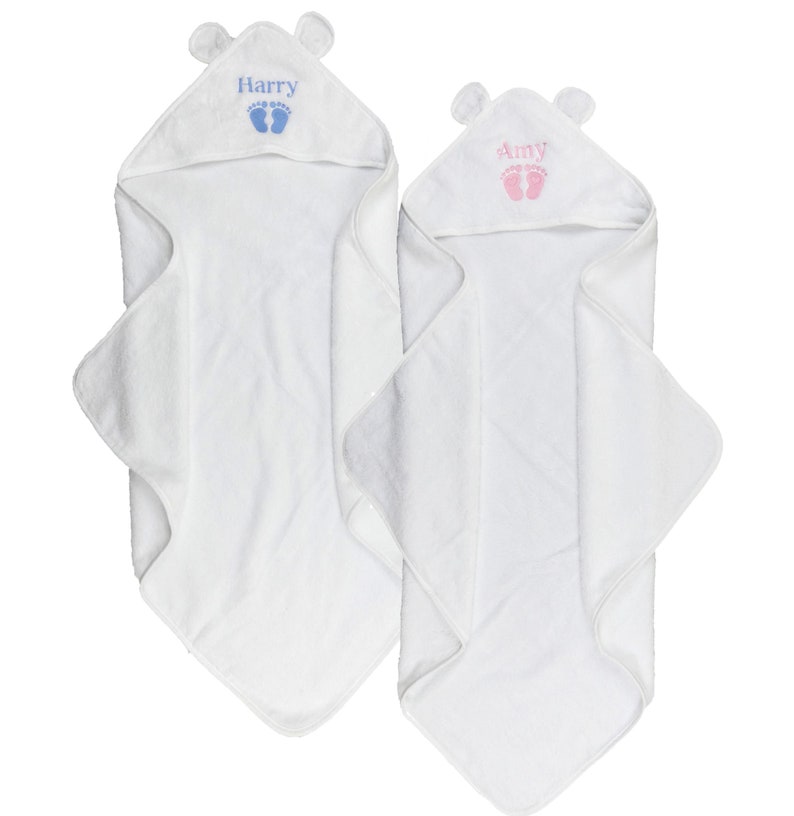 May include: Two white hooded baby towels with bear ears. One towel has the name "Harry" embroidered in blue with blue footprints, the other has "Amy" in pink with pink footprints. The towels are folded.