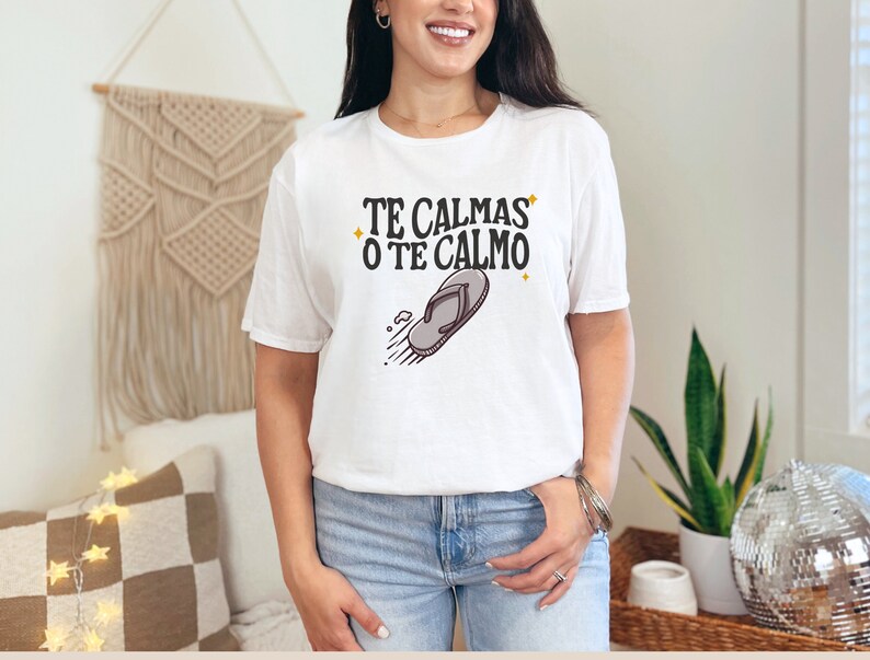 May include: White t-shirt featuring the text "TE CALMAS O TE CALMO" in black and a flip-flop graphic. The casual t-shirt is suitable for everyday wear.