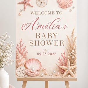 Może przedstawiać: Prostokątna tablica powitalna na baby shower z napisem 'WELCOME TO Amelia's BABY SHOWER 09.25.2026'. Projekt zawiera ilustracje różowych rozgwiazd, muszli, piaskowców, pereł i suszonej trawy pampasowej na jasnym tle.