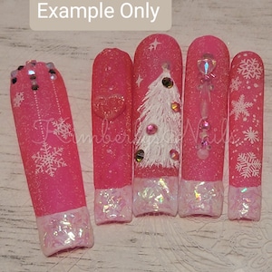 Può includere: Cinque unghie artificiali rosa con disegni di fiocchi di neve e alberi di Natale bianchi. Le unghie hanno una finitura scintillante e punte iridescenti.
