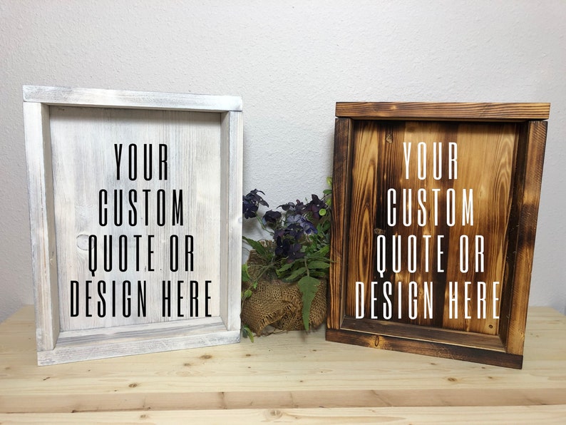 May include: Two wooden framed signs with the text "YOUR CUSTOM QUOTE OR DESIGN HERE". One sign is painted white, the other is stained brown. Both signs are square and sit on a wooden surface.