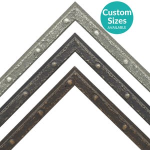 May include: Three picture frame moldings with a textured, hammered metal finish. The moldings are in three different colors: silver, dark gray, and bronze. Each molding has a row of raised metal studs along the edge. The text "Custom Sizes Available" is in a circle on the image.