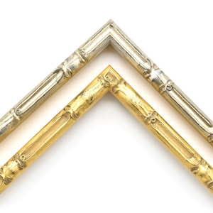 May include: Two picture frames, one gold and one silver, with a decorative bamboo design. The frames are both angled to show the corner.