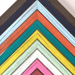 May include: A set of 10 wooden picture frames in various colors, including teal, yellow, pink, and white. The frames are arranged in a chevron pattern, with the widest frame at the top and the narrowest frame at the bottom.