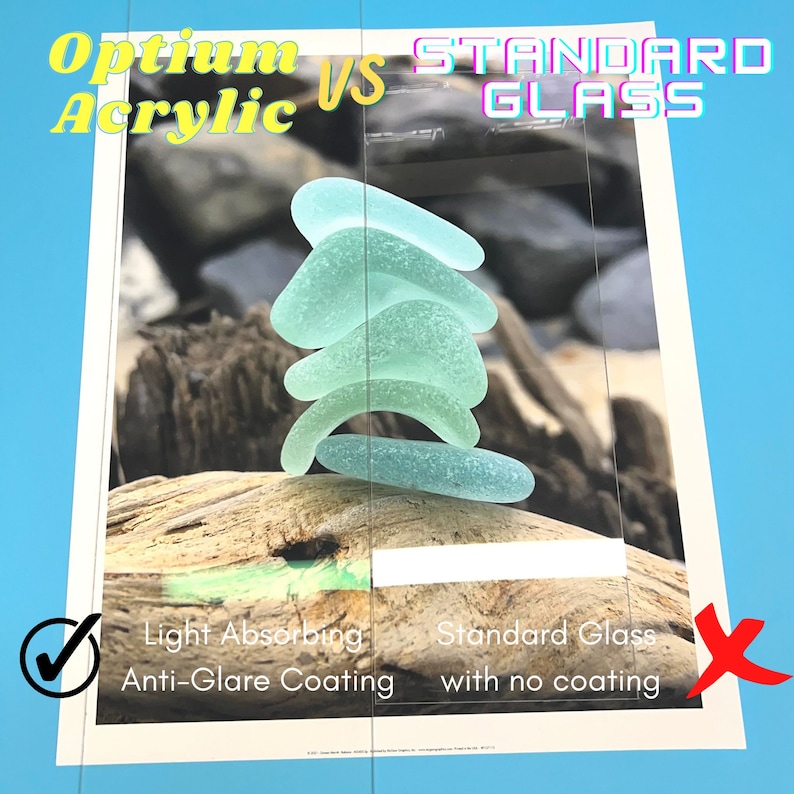 May include: A side-by-side comparison of two pieces of glass, one with an anti-glare coating and one without. The glass with the anti-glare coating is labeled "Optium Acrylic" and the glass without the coating is labeled "Standard Glass". Both pieces of glass are clear and have a smooth surface. A stack of sea glass is placed on top of each piece of glass.
