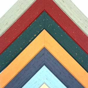 May include: A set of seven wooden picture frames in various colors, including light green, red, dark green, orange, dark blue, light blue, and cream. The frames are arranged in a chevron pattern.