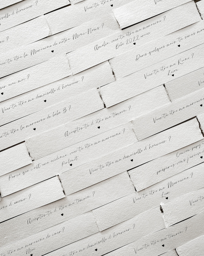 May include: White paper strips with black text asking "Will you be my..." followed by a role in a wedding party, such as "maid of honour", "matron of honour", "bridesmaid", or "godmother".