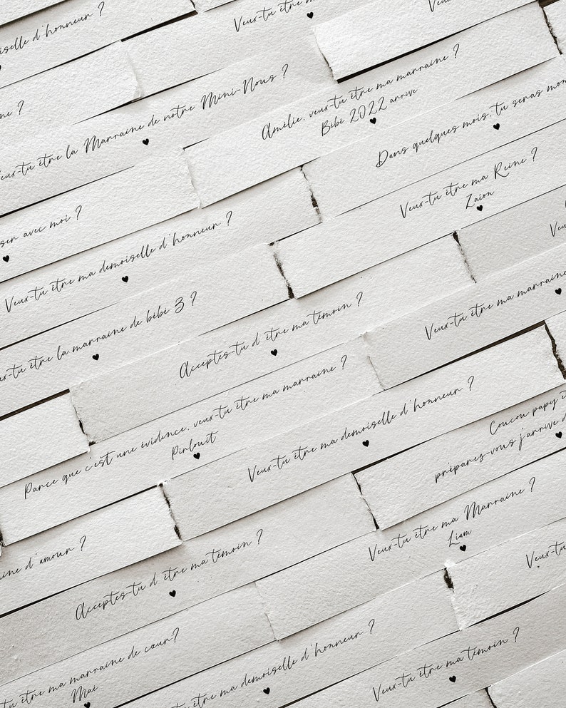 May include: White paper strips with black text asking "Will you be my..." followed by a role in a wedding party, such as "maid of honour", "matron of honour", "bridesmaid", or "godmother".