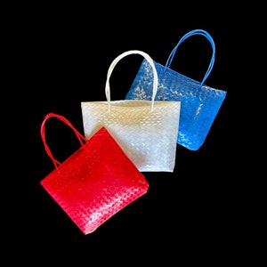 May include: Three woven tote bags in red, white, and blue. The bags have a woven pattern and are made of a plastic material.