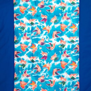 May include: A blue fabric with a white and pink pattern of pigs flying in the sky. The fabric has a white background with blue clouds and pink pigs with rainbow wings.