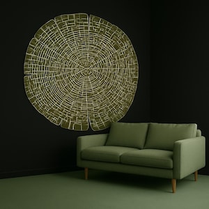 Könnte beinhalten: Ein großes, kreisförmiges Wandkunstwerk, das einem Baumquerschnitt ähnelt, in Olivgrün und Gold, hängt an einer dunklen Wand. Darunter befindet sich ein grünes Sofa mit Holzbeinen. Der Raum hat eine moderne, minimalistische Ästhetik.