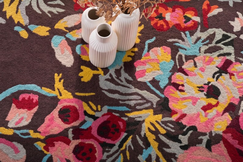 Overhead detail shot of a floral rug with spools of colorful wool yarn resting on top to highlight craft materials.