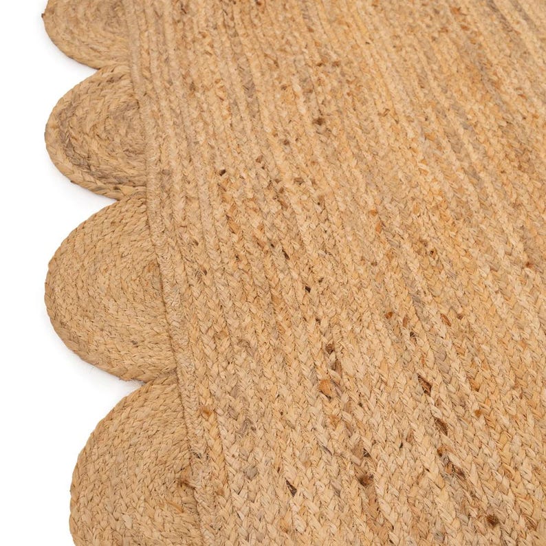 K&ouml;nnte beinhalten: Ein Naturfaser-Teppich mit einem gewellten Rand. Der Teppich ist aus gewebtem Jute gefertigt und hat eine hellbraune Farbe.