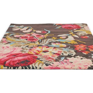 Colourful wool area rug styled beneath a neutral sofa in a contemporary living room.Ground-level perspective photograph of a dark brown wool area rug with pink and red floral patterns extending across the room.
