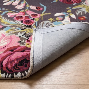Close-up photograph of the corner of a hand-tufted rug turned over to display the sturdy canvas backing, finished edge, and tufted front pile.