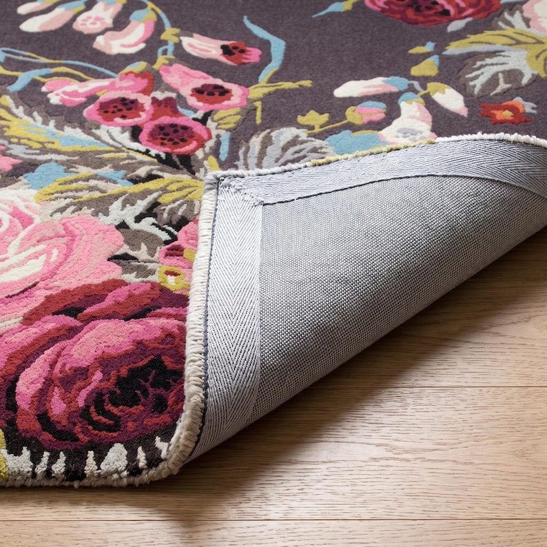 Close-up photograph of the corner of a hand-tufted rug turned over to display the sturdy canvas backing, finished edge, and tufted front pile.