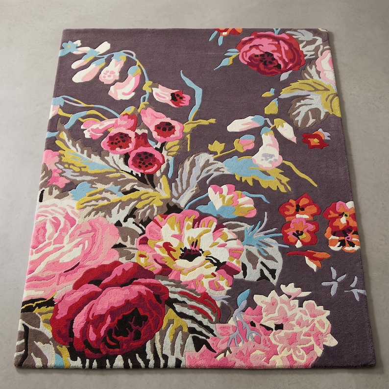 High-angle complete product view of a rectangular hand-tufted dark brown floral area rug lying flat on a smooth floor.
