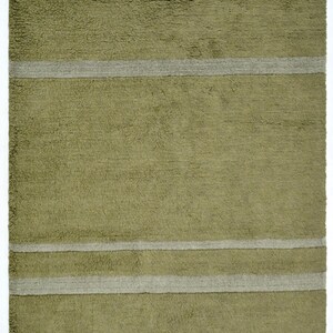 Pode incluir: Um tapete retangular verde-oliva com listras cinza horizontais. O tapete tem uma superf&iacute;cie texturizada e franjas nas bordas superior e inferior. Um item de decora&ccedil;&atilde;o para casa.