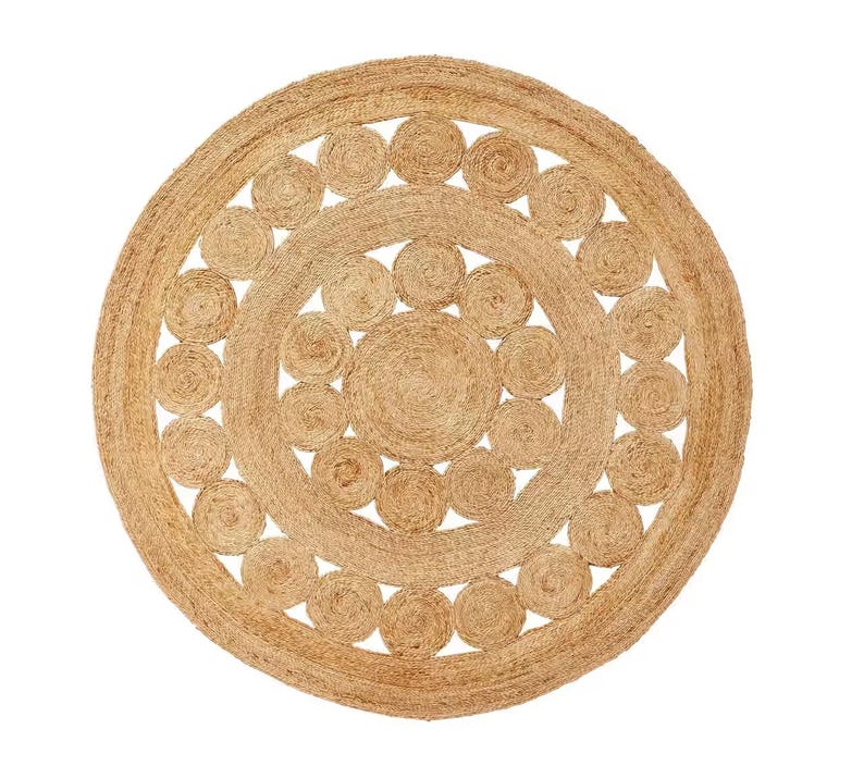 May include: A round, natural fiber rug with a circular pattern of woven circles. The rug is made of jute and has a natural, earthy color.