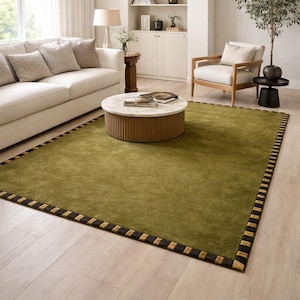 Peut inclure: Tapis rectangulaire vert olive avec une bordure noire et dor&eacute;e. Le tapis est dans un salon avec un canap&eacute; cr&egrave;me, une chaise en bois et une table basse ronde. Dimensions en cm.