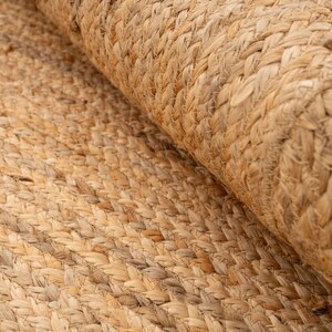 K&ouml;nnte beinhalten: Nahaufnahme eines Naturfaser-Teppichs aus gewebtem Jute. Der Teppich hat eine hellbraune Farbe und ein strukturiertes, gewebtes Muster.