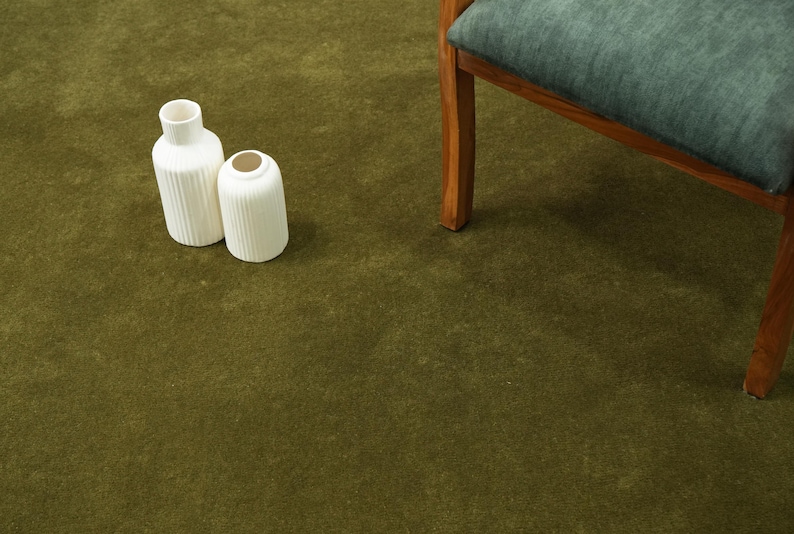 Peut inclure: Deux vases en c&eacute;ramique blanche avec des d&eacute;tails c&ocirc;tel&eacute;s sur un tapis vert. L'un est grand et cylindrique, l'autre est plus court et arrondi. Une chaise en bois avec un coussin bleu-vert est en arri&egrave;re-plan.