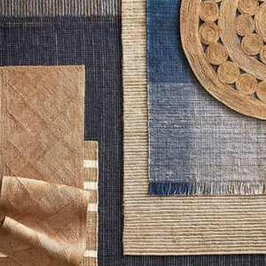 May include: A set of four woven rugs in various shades of brown and blue. The rugs are made of natural fibers and have a textured surface. The rugs are arranged in a grid pattern, with the largest rug in the center.