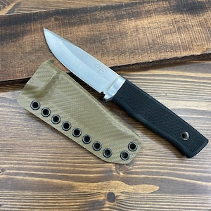 May include: A fixed-blade knife with a silver steel blade, a black textured handle, and a tan carbon fiber patterned sheath featuring a row of black metal eyelets. The blade is etched with the text F1 Pro Fallkniven.