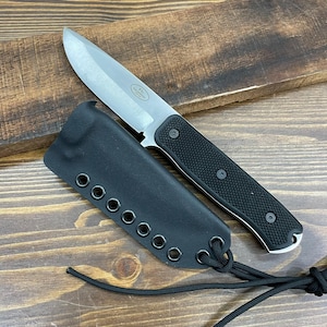 May include: A stainless steel knife with a black textured handle and a black sheath. The knife blade is silver and the handle is secured with three black screws. The sheath has multiple eyelets and a black cord.