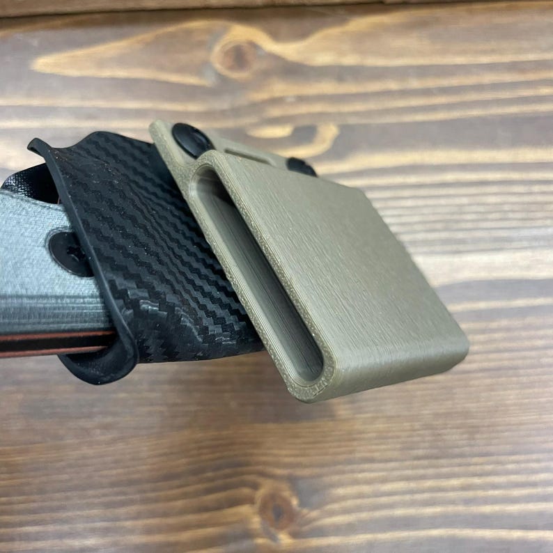 Puede incluir: Dos estilos diferentes de fundas para un cuchillo. Una es negra con un patr&oacute;n de fibra de carbono y la otra es de color marr&oacute;n claro.