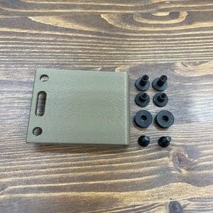 Puede incluir: Una placa de montaje de pl&aacute;stico de color beige con tres agujeros y una ranura. La placa viene acompa&ntilde;ada de seis tornillos y arandelas negros.