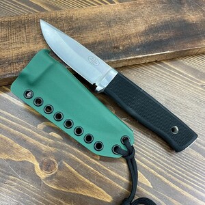 May include: A stainless steel knife with a black textured handle and a green sheath. The knife has a sharp blade and is designed for outdoor use. The sheath has multiple eyelets and a black cord for securing the knife.