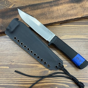 Puede incluir: Un cuchillo de acero inoxidable con un mango negro texturizado y una funda negra. La hoja del cuchillo es plateada y el mango tiene un acento azul. La funda tiene ojales y un cordón negro.